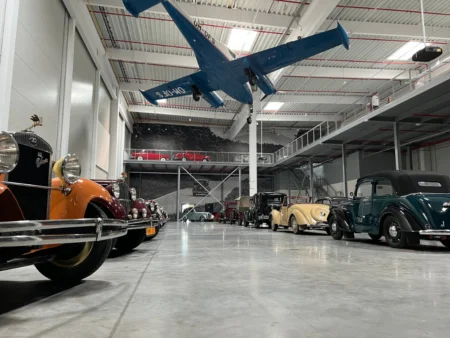 Interiér múzea Oldtimer Gallery s historickými autami zaparkovanými v hale a lietadlom zaveseným pod stropom