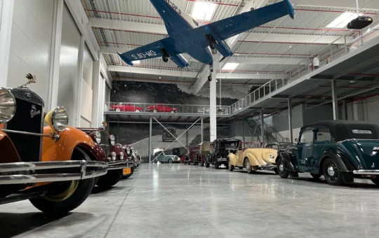 Interiér múzea Oldtimer Gallery s historickými autami zaparkovanými v hale a lietadlom zaveseným pod stropom