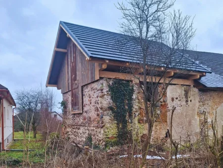 Historická Pekáre kúria v Kľačanoch pri Pravenci s obnovenou strechou, kamenným murivom a drevenou nadstavbou.