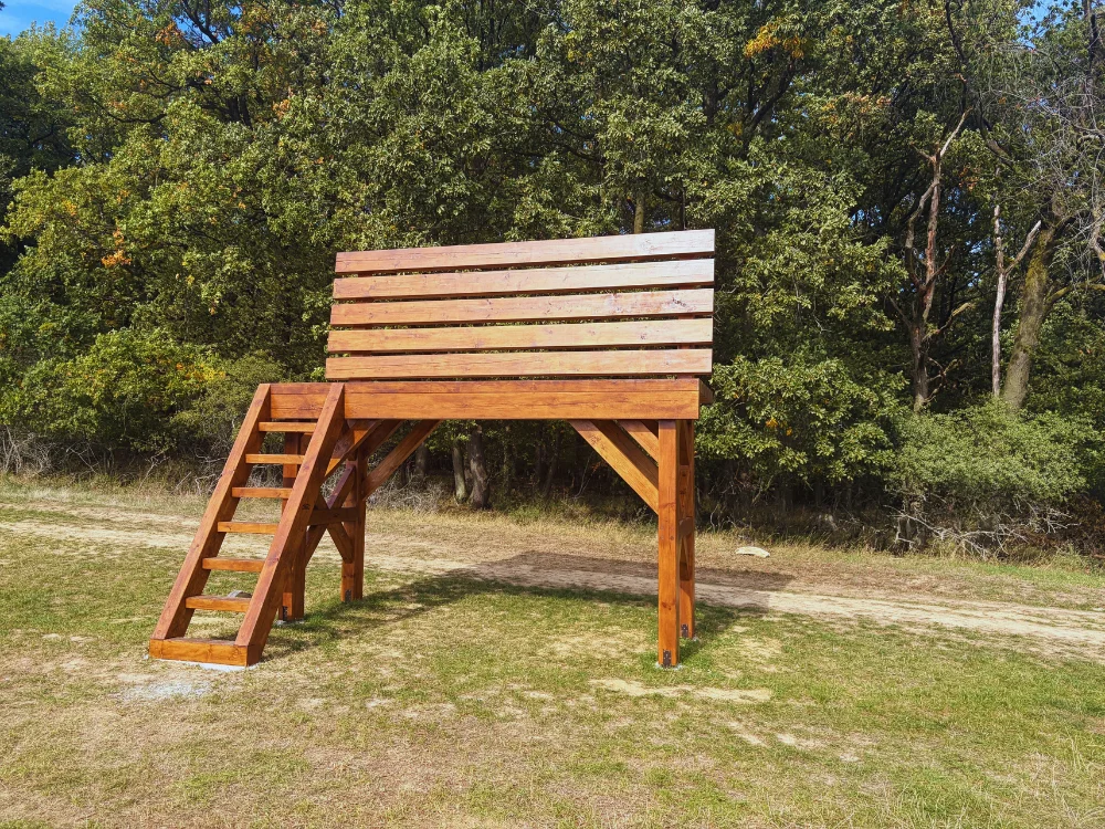 Obrovská drevená lavička pri lese s výhľadom na okolité polia a kopce v okolí Brezolúp.